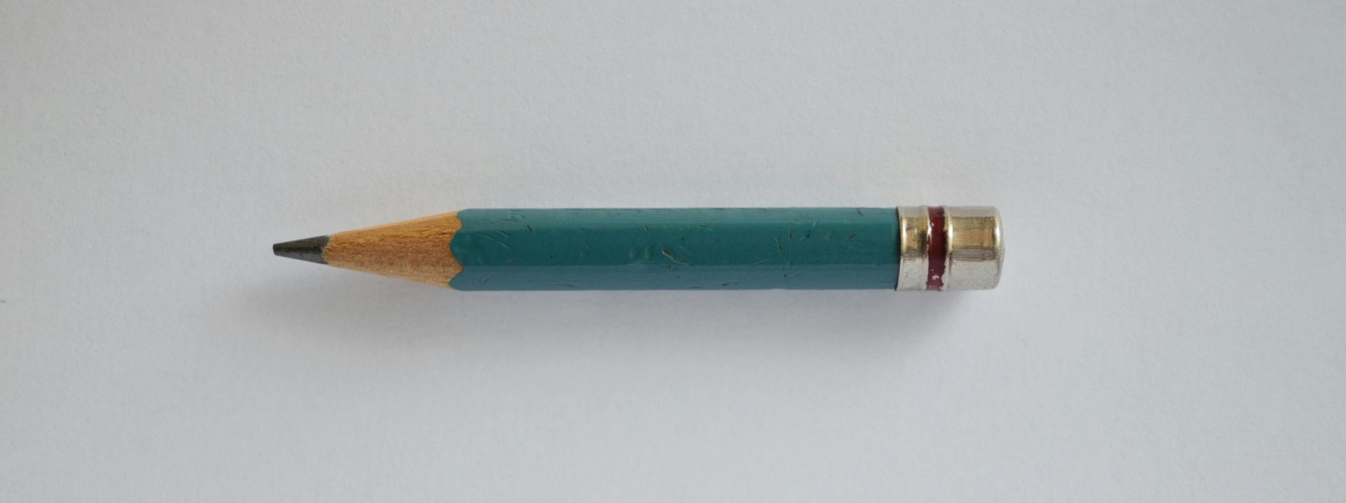 Minimalist image of a sharpened green pencil on a plain white background.