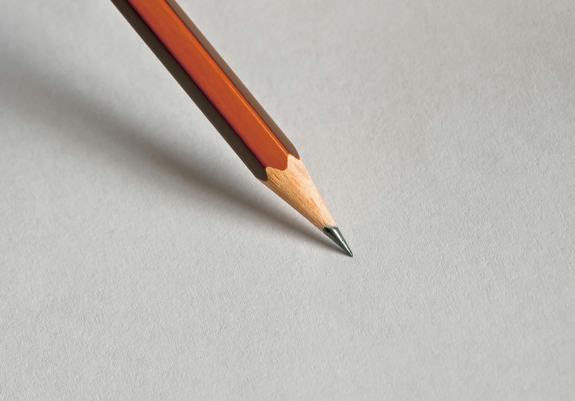 Detailed close-up of a wooden pencil resting on white paper, perfect for educational themes.
